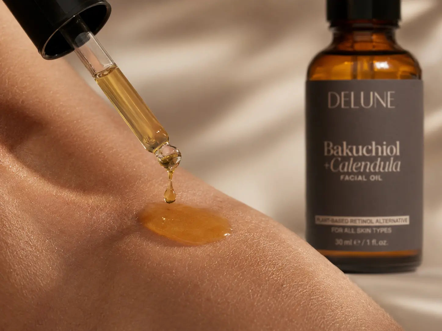 Golden facial oil falling from a pipette onto skin beside the Delune bottle